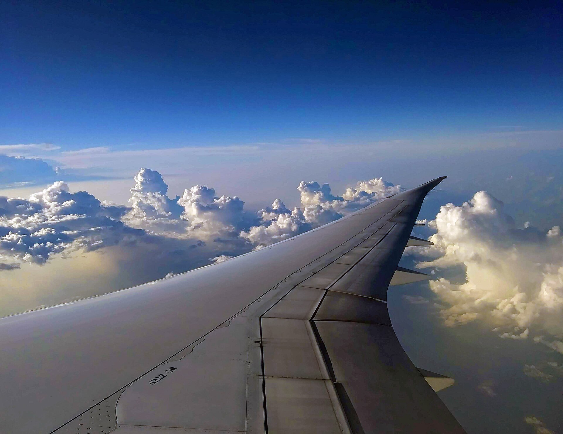 View from an airliner window of the wing above a deck of clouds
